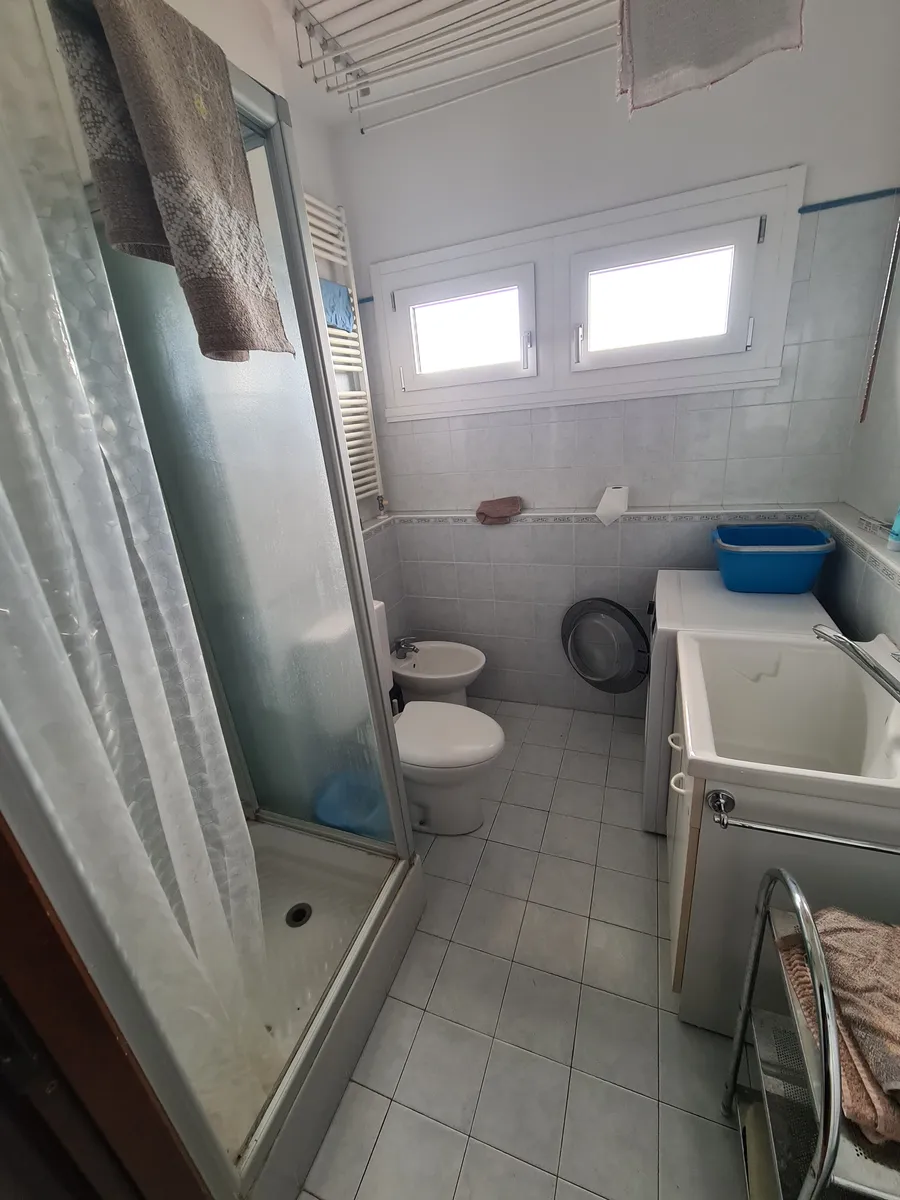 Lo stesso bagno prima, con la vecchia tenda della doccia e gli oggetti in vista