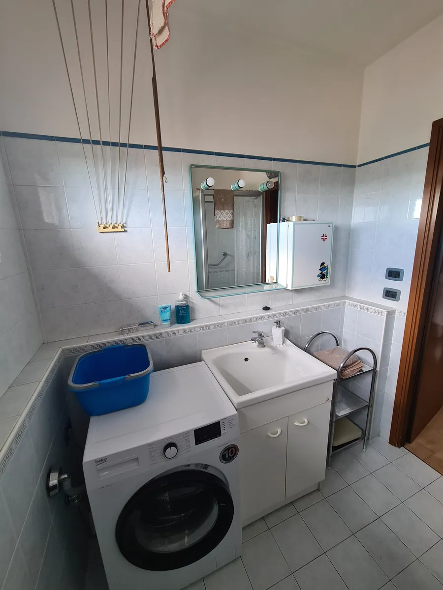 Lo stesso bagno prima, con la lavatrice, il cesto e lo stendino in mezzo