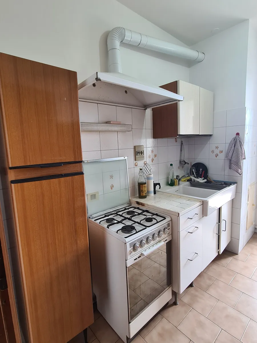 La stessa cucina prima, con i mobili in legno scuro e gli elettrodomestici a vista