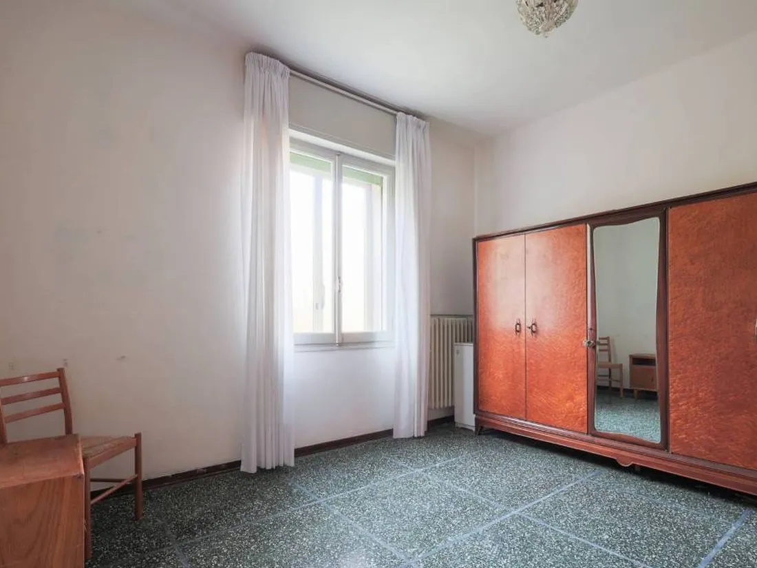 La stessa camera prima, con armadio d'epoca e pavimento scuro