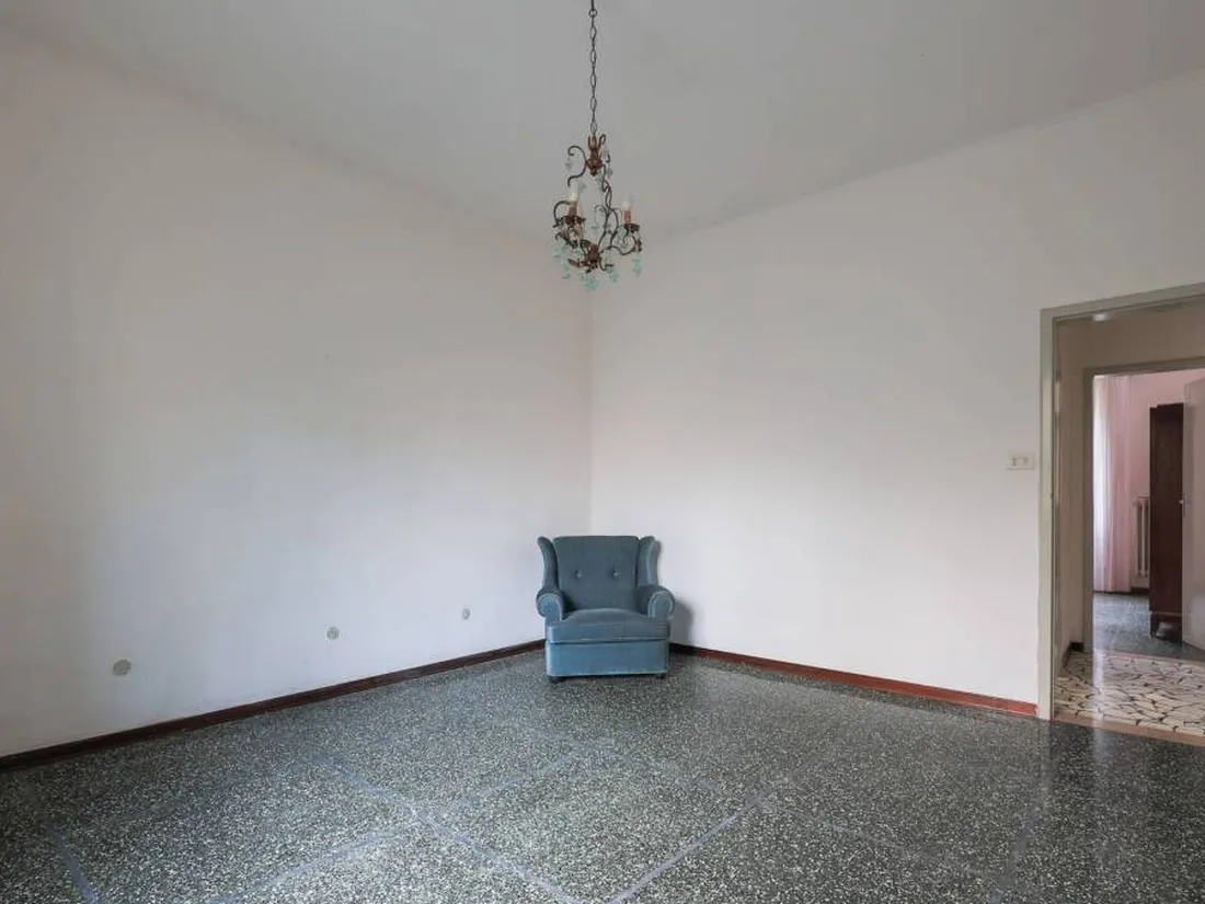 La stessa stanza prima, vuota con pavimento scuro