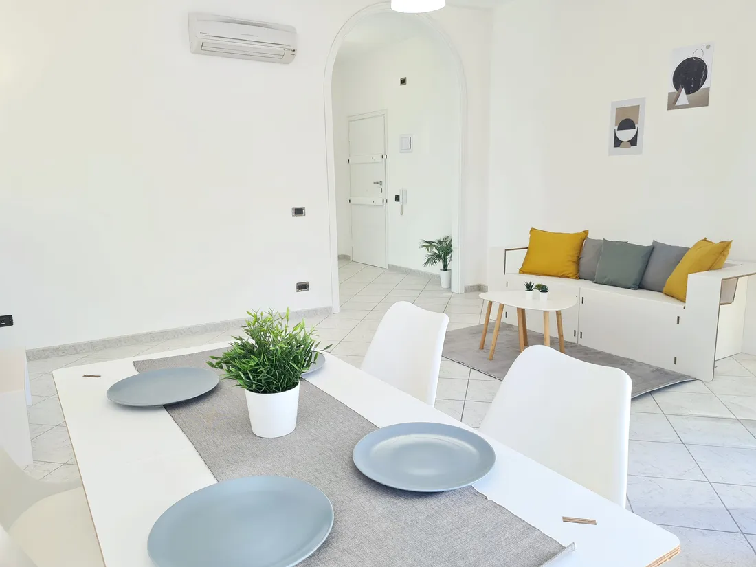 Soggiorno con tavolo apparecchiato e divano dopo l'home staging