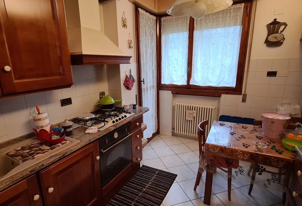 Cucina di via Misa prima dell'intervento, con mobili scuri e piano ingombro