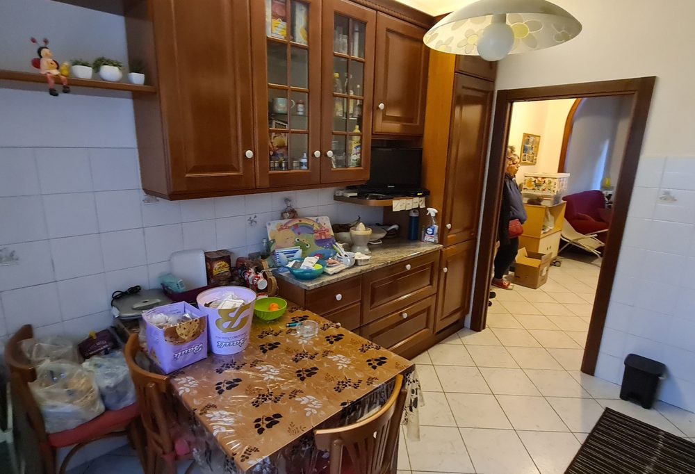 Angolo pranzo della cucina di via Misa prima, con tavolo e ripiani ingombri