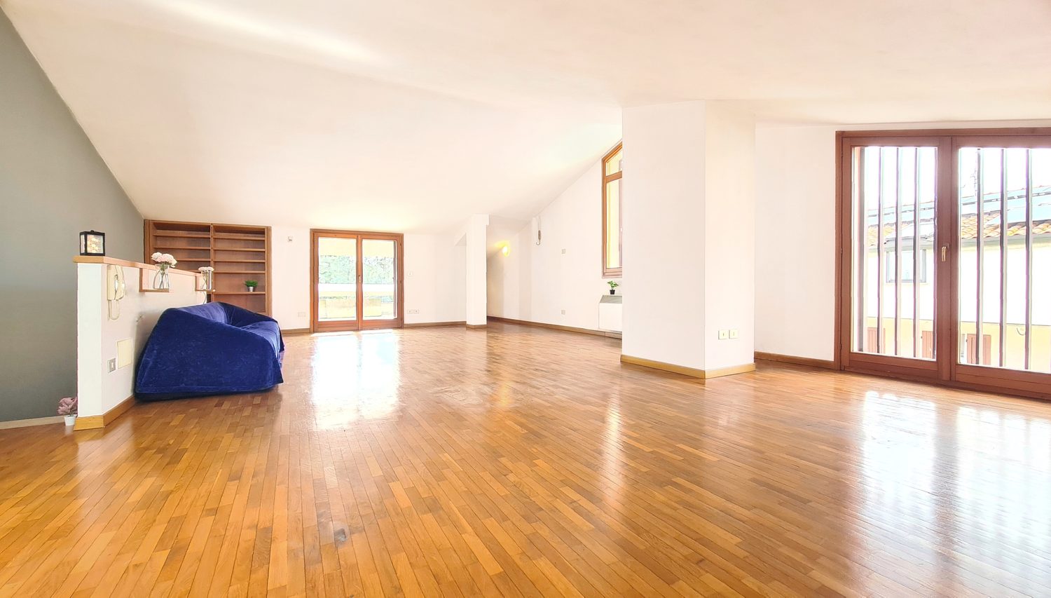 Grande salone mansardato luminoso con parquet e soffitto spiovente